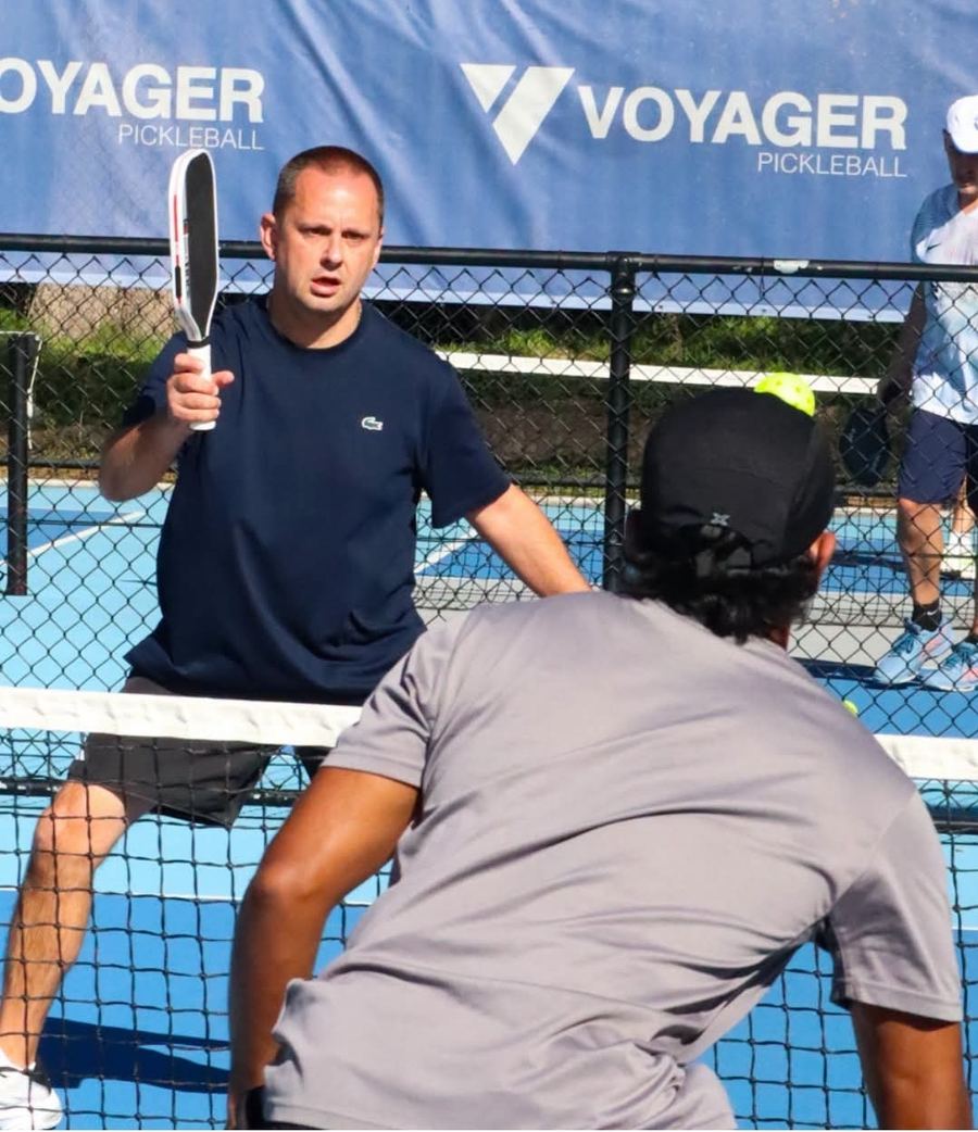 Players at the net during a pickleball rally at Voyager Tennis